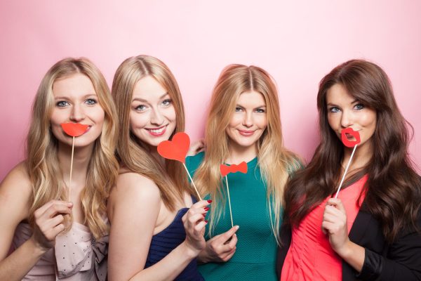 Freundinnen vor Fotobox mit Utensilien