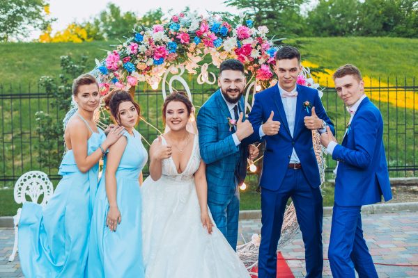 elegant stylish happy guests and bride and groom having funny photos on the background of arch, photo booth. Wedding moments with bridesmaids and groomsmen.