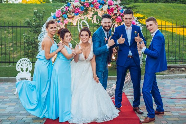 elegant stylish happy guests and bride and groom having funny photos on the background of arch, photo booth. Wedding moments with bridesmaids and groomsmen.