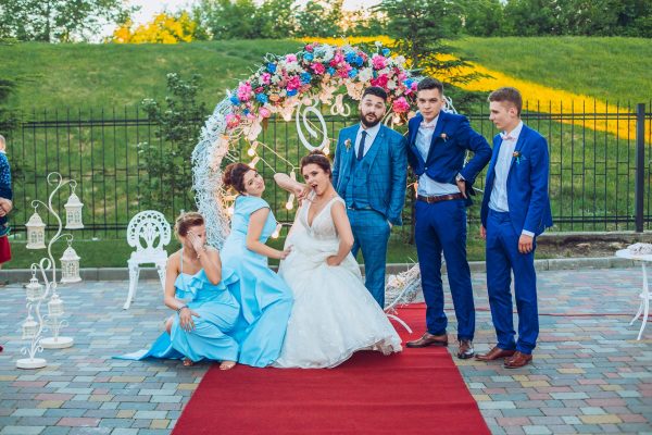 elegant stylish happy guests and bride and groom having funny photos on the background of arch, photo booth. Wedding moments with bridesmaids and groomsmen.