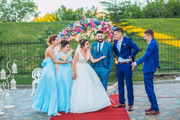 elegant stylish happy guests and bride and groom having funny photos on the background of arch, photo booth. Wedding moments with bridesmaids and groomsmen.