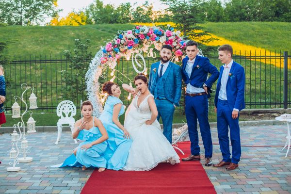 elegant stylish happy guests and bride and groom having funny photos on the background of arch, photo booth. Wedding moments with bridesmaids and groomsmen.