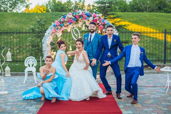 elegant stylish happy guests and bride and groom having funny photos on the background of arch, photo booth. Wedding moments with bridesmaids and groomsmen.